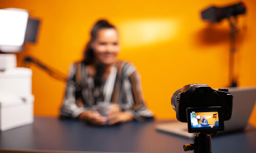 A woman recording video with a camera on a table