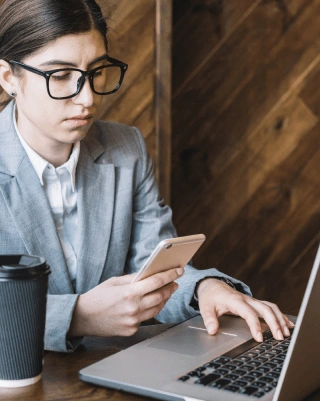 Expert translator using a laptop and smartphone for phone call transcription services for businesses and individuals.