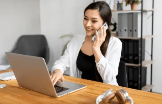  A woman talking on the phone while working on a laptop