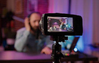 Digital video camera screen recording male vlogger with headphones talking at microphone at home