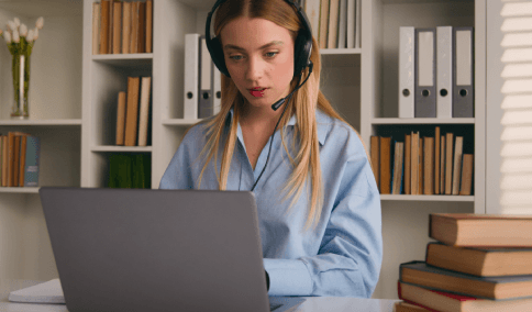 Woman wearing a headset and working  on a laptop, showcasing certified transcription services with reliable customer support.