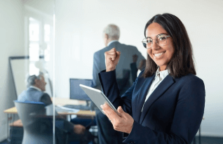 A Female Professional in Glasses and Suit Holding Tablet and Making Winner Gesture