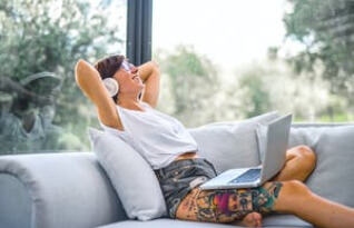  A happy woman with headphones and a laptop on her lap