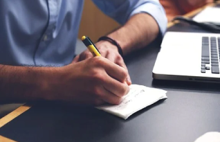 Transcriber on his work station writing on a notepad 