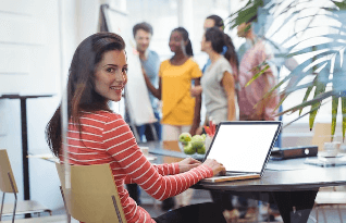 A person working on a laptop with native employees discussing at the back