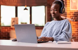 A native American with headphones working on a laptop