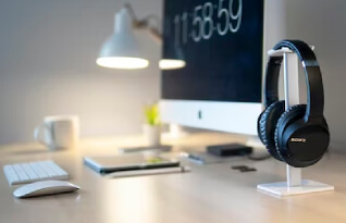 Work space with Sony headphones placed on a stand at the fore front.