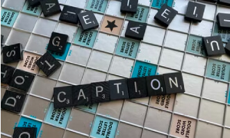 The word CAPTION spelled out in Scrabble tiles