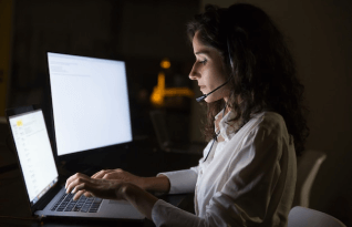  Focused businesswoman in headset using laptop