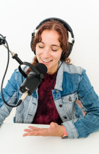 A woman recording a podcast with mic and headphones