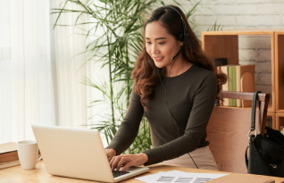A smiling transcriber on work station with a head set on 