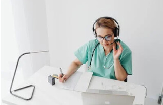  A woman with doctor's outfit taking notes while listening on a headset